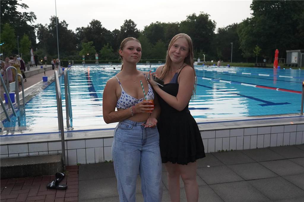 Fotos vom Nachtschwimmen 2024 im Freibad Castrop-Rauxel bei Regen. Besucher schwimmen unter freiem Himmel bei Fackelschein am Abend. Entspannte Atmosphäre und kulinarisches Angebot. 
