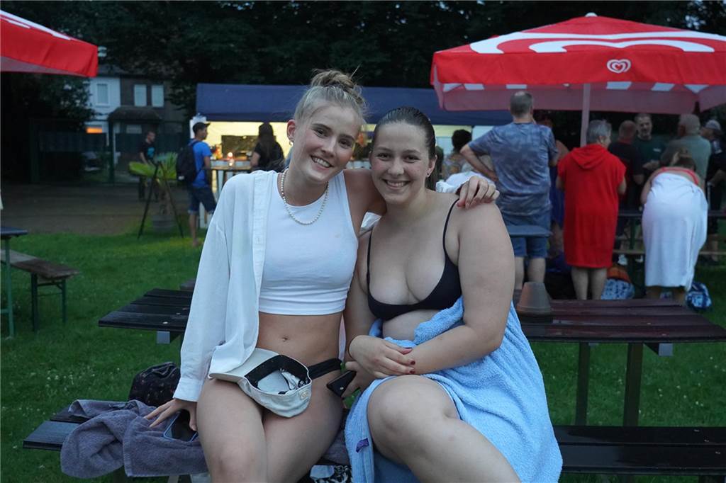 Fotos vom Nachtschwimmen 2024 im Freibad Castrop-Rauxel bei Regen. Besucher schwimmen unter freiem Himmel bei Fackelschein am Abend. Entspannte Atmosphäre und kulinarisches Angebot. 

