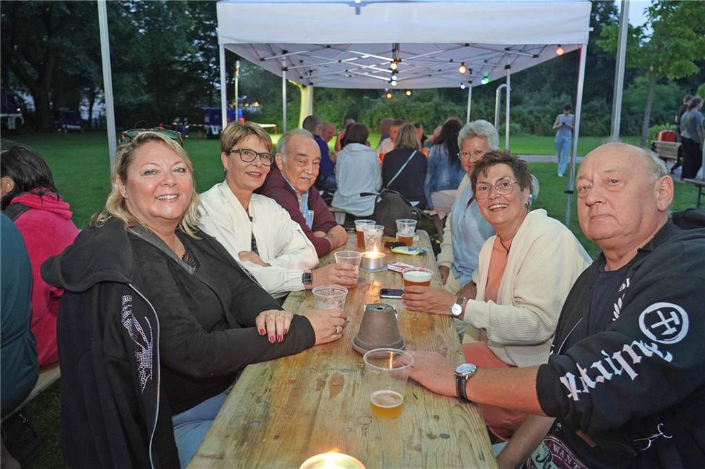 Fotos vom Nachtschwimmen 2024 im Freibad Castrop-Rauxel bei Regen. Besucher schwimmen unter freiem Himmel bei Fackelschein am Abend. Entspannte Atmosphäre und kulinarisches Angebot. 
