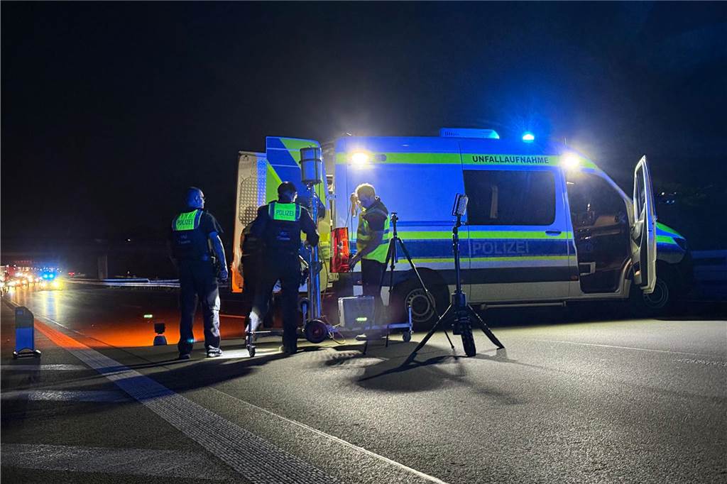 Mitglieder des VU-Teams der Polizei stehen vor einem Polizeifahrzeug im Scheinwerferlicht. 