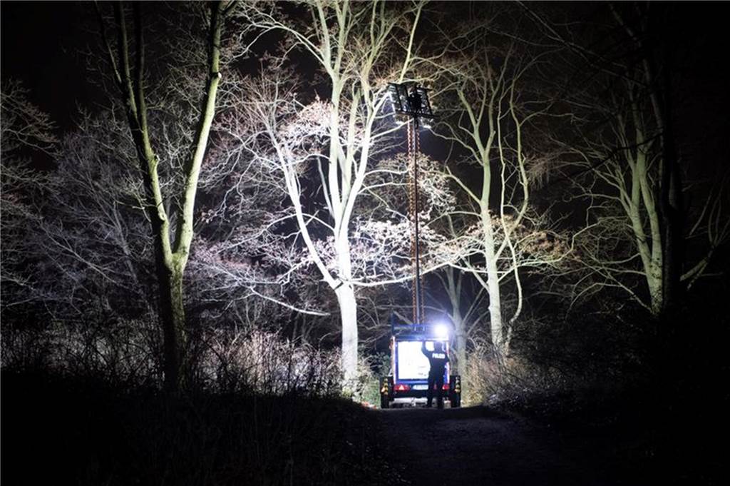 Polizisten beleuchten im Dunkeln einen Ort an einem Park in Pankow.