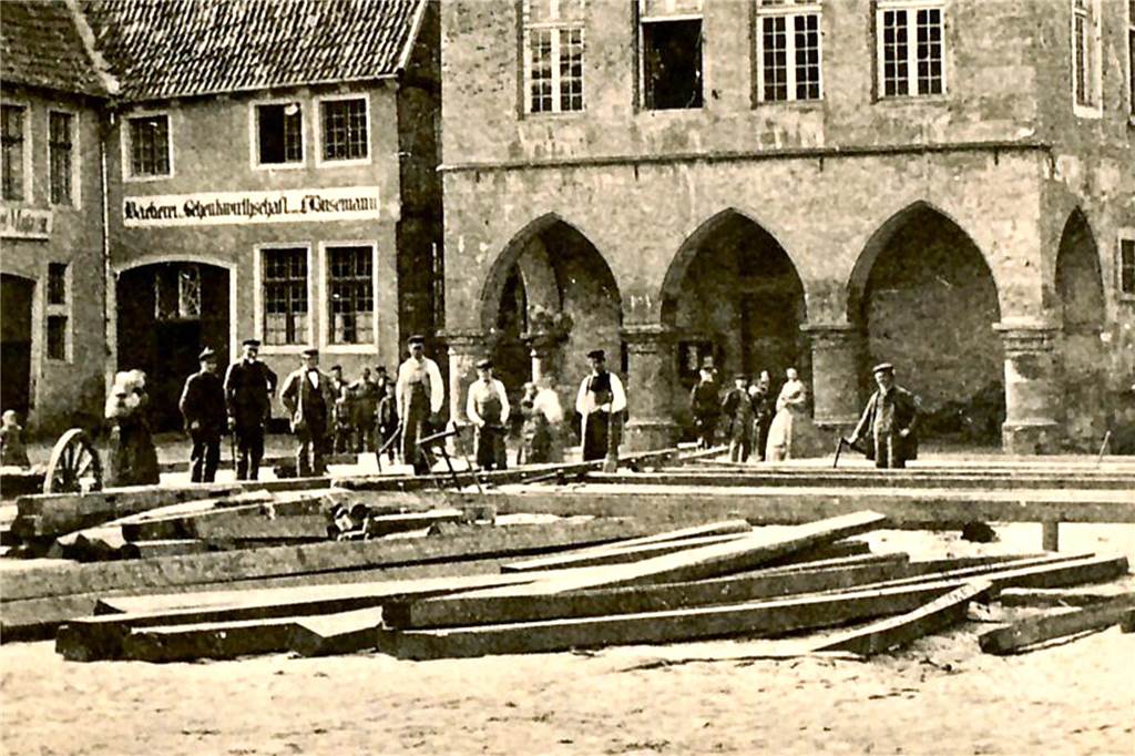 Das wahrscheinlich älteste Foto des historischen Rathauses zeigt auch den Marktplatz, der damals freilich noch anders aussah. Entstanden ist das Bild wohl um 1890. Es zeigt eine kleine Gruppe von Menschen und auf dem Boden liegende Holzbalken.