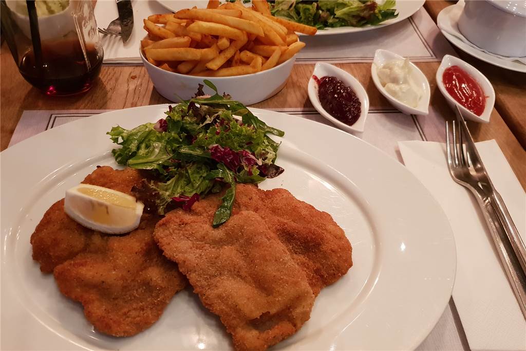 Großes kulinarisches Kino zu gesalzenen Preisen im Leuthold’s 1910 Das Wiener Schnitzel vom Kalbslachs überzeugt mit tollem Fleischgeschmack, fluffig aufliegender Panade und Preiselbeeren. Dazu gibt es Pommes mit Mayonnaise und Ketchup.