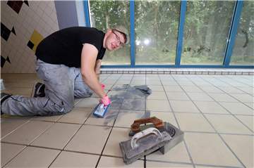 David Schenk von der Firma Schicht und Adrian muss die neuen Fugen im Hallenbad fünf mal öfter waschen als in einem normalen Badezimmer. Spezielles Fugenmaterial macht die Sanierung aufwendig.