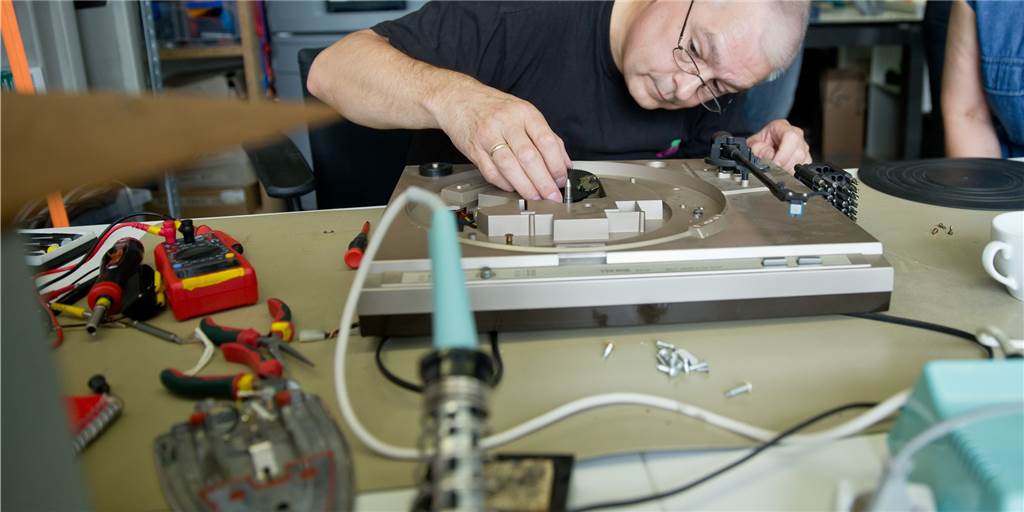 Elektrogeräte richtig kaufen - und das Klima schützen In einem Repair-Cafe zerlegt ein Techniker einen alten und defekten Plattenspieler, um ihn wieder funktionstüchtig zu machen.