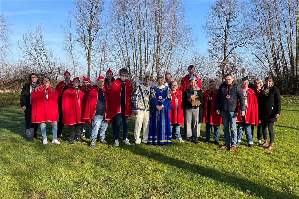 Prinz Sascha und Prinzessin Manuela führen durch die Session Das Prinzenpaar steht umringt von Pagen in roten Mänteln auf einer Wiese vor den Caritas-Werkstätten.