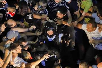 Demonstrationsteilnehmer haben einen gestürzten Polizisten vor dem Regierungssitz in Bukarest. Foto: Vadim Ghirda/AP