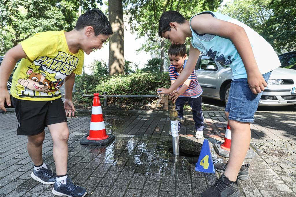 Nach Brand: Hochhaus hat kein Wasser mehr – Bewohner müssen zum Hydranten Den Kindern bereitet die Zapfstelle in der Sonntagnachmittags-Hitze Freude.