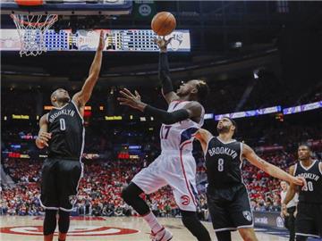 Dennis Schroeder (M) wird bei einem Korbleger von zwei Spielern der Nets geblockt. Foto: Erik S. Lesser