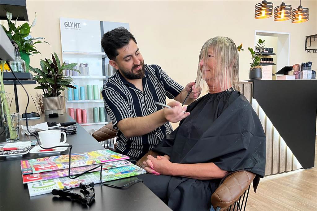 Flucht, Ausbildung, Meister: Hamo Qasim eröffnet Haarstudio Hamo Qasim schneidet einer Kundin in seinem Haarstudio die Haare.