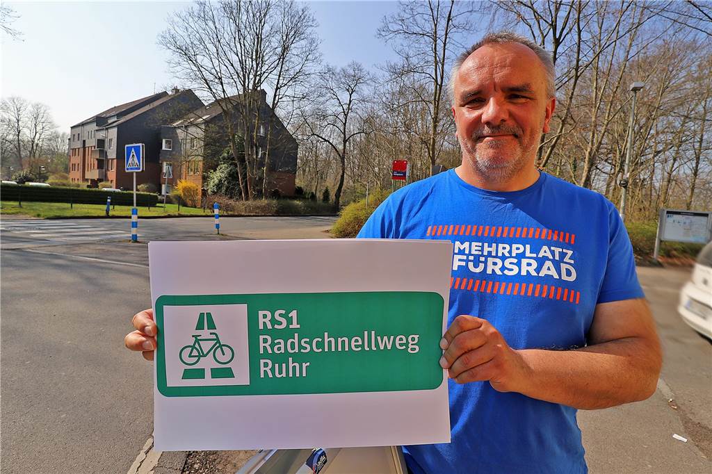 Der 1. Vorsitzende des ADFC-Kreisverbandes Unna Dr. Andreas Abel hält ein Werbeschild für den Radschnellweg Ruhr in die Höhe.