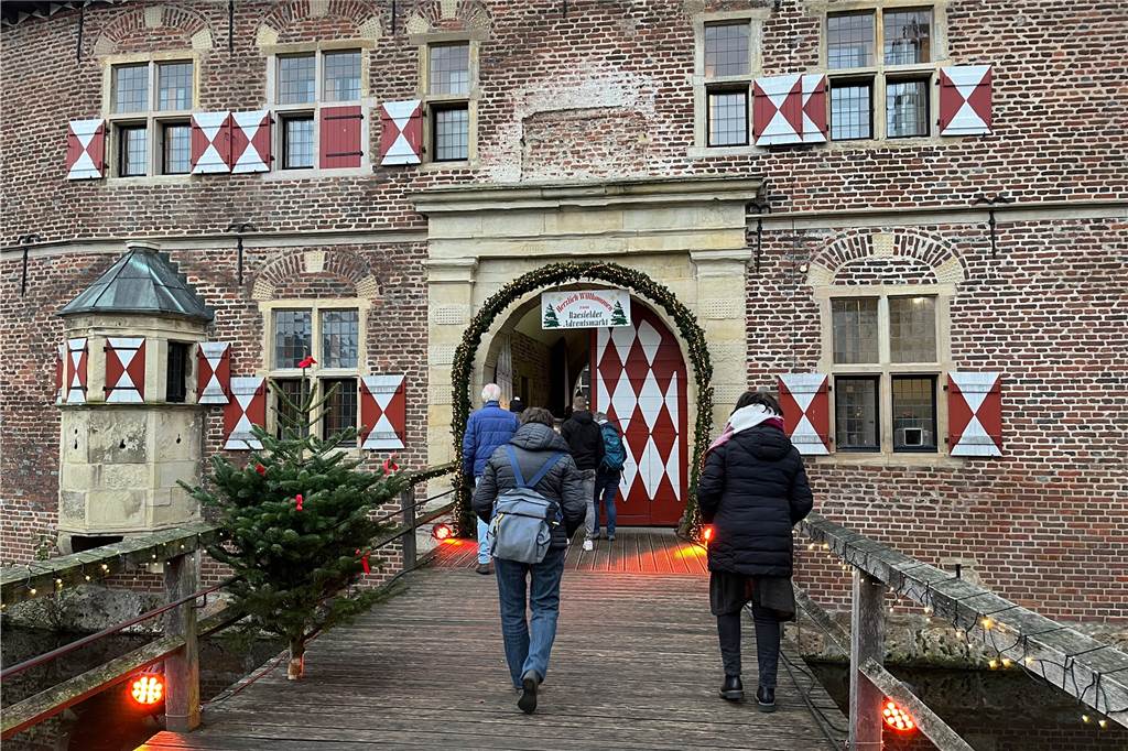 Ein paar Menschen laufen über die weihnachtlich geschmückte Schlossbrücke in den Innenhof.