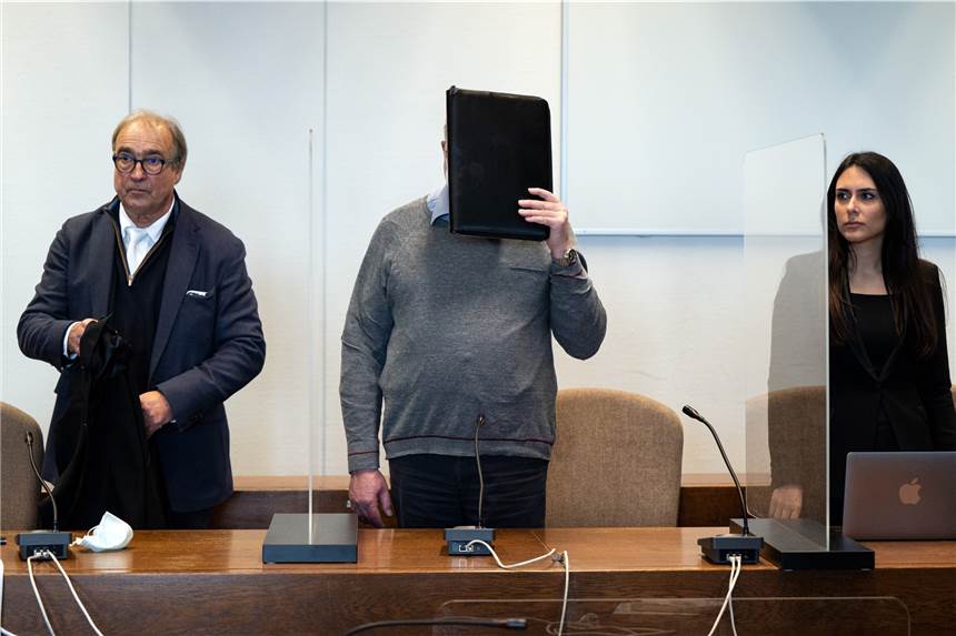 Wegen Missbrauch angeklagter Priester: Verhandlung verschoben Der angeklagte katholische Priester (M) hält sich im Gerichtssaal eine Mappe vor das Gesicht. Er wird wegen sexuellen Missbrauchs angeklagt. Der 70-Jährige soll in den 1990er Jahren in 31 Fällen seine damals zwischen 7 und 13 Jahre alten Nichten missbraucht haben.