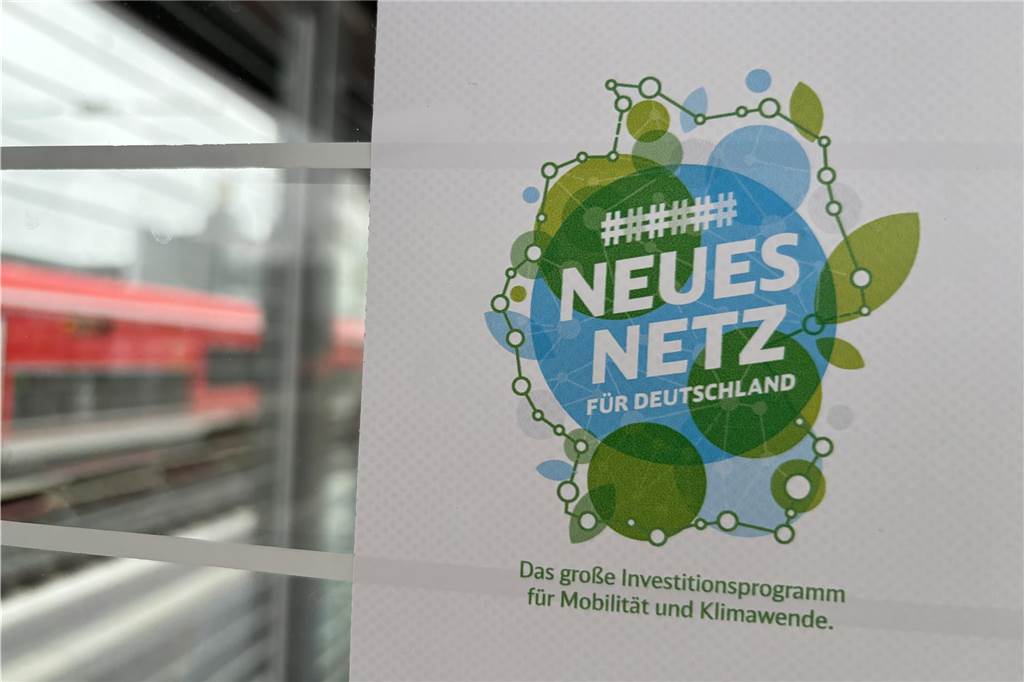Behinderungen im Bahnverkehr: Baustelle wurde nicht rechtzeitig fertig Plakat zu den Invesitionsmaßnahmen der Deutschen Bahn an einer Glasscheibe auf dem Bahnsteig in Dortmund. Im Hintergrund eine rote Regionalbahn.