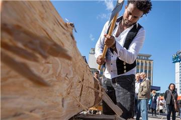 Der Auszubildende Samuel Shishay, ein Flüchtling aus Eritrea, behaut beim Tag des Handwerks einen Balken nach traditioneller Art im thüringischen Suhl. Foto: arifoto UG