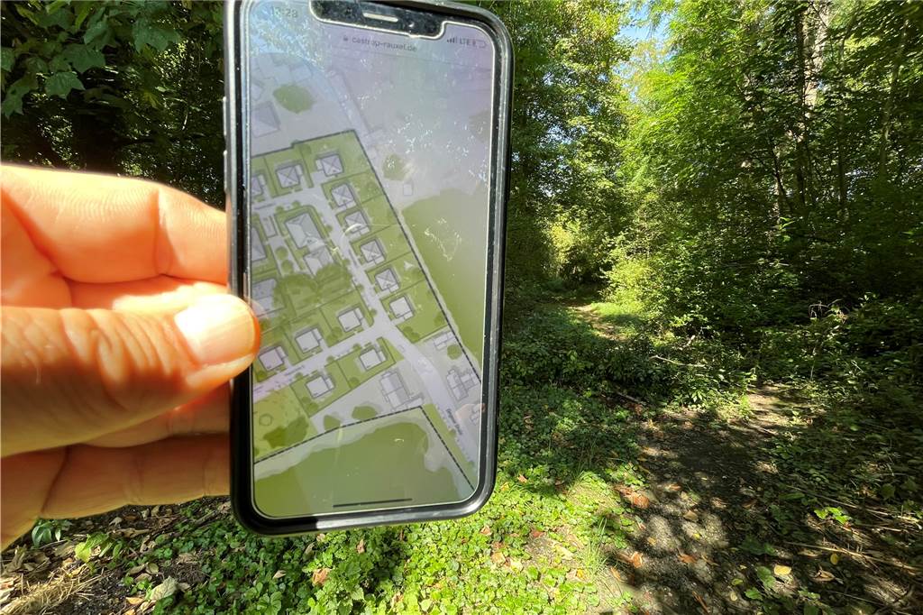 Ärger um Baugebiet in Castrop-Rauxel: „Von Intimsphäre kann keine Rede sein“ Auf einem Smartphone-Display ist der Bebauungsplanentwurf zum Neubaugebiet in Dingen zu sehen. Im Hintergrund der reale Waldweg.