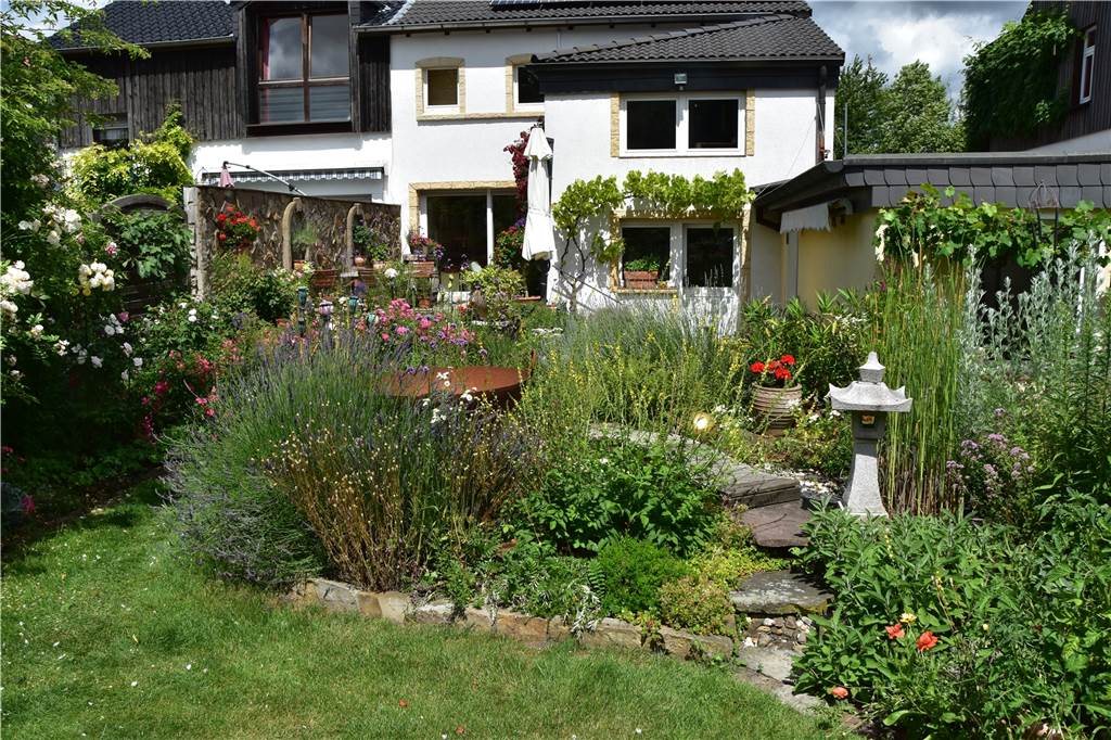 Dortmunder Senioren sind stolz auf 750 Quadratmeter wilden Naturgarten Der Blick vom Garten auf das Haus. Zwischen den Blumen steht eine Feuerstelle.