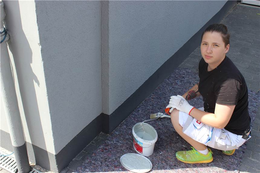 Könner mit Pinsel und Farbe Der Boden ist mit Malervlies geschützt, die Arbeit kann beginnen: Janine Kolmanic ist bereit, den Sockel der Fassade zu streichen. Foto: Starb