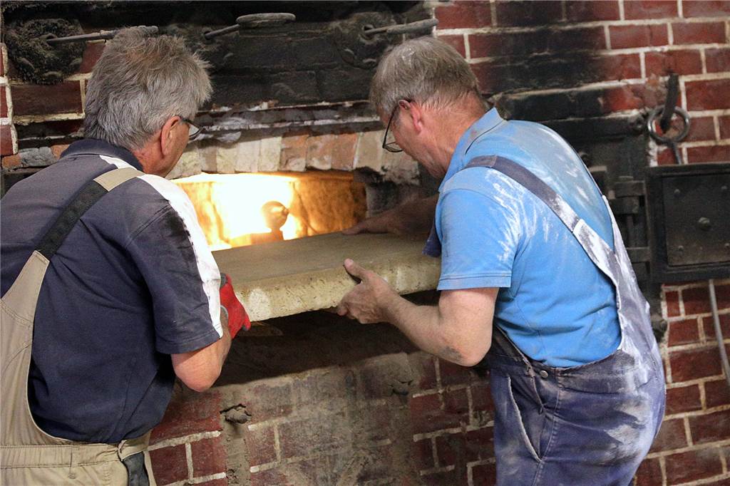 Neue Steine für historischen Backofen bei Balke: Handwerker geben alles Der erste von 15 Tuffsteinen wird in den Ofen eingesetzt.