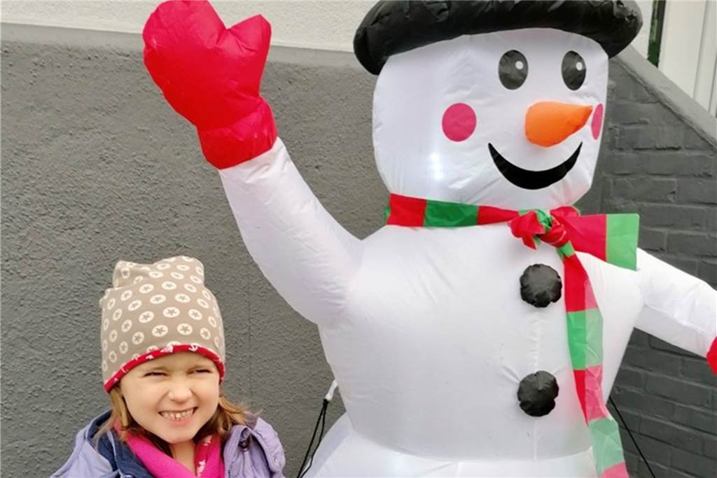Lylou steht neben einem aufgeblasenen Plastik-Schneemann.