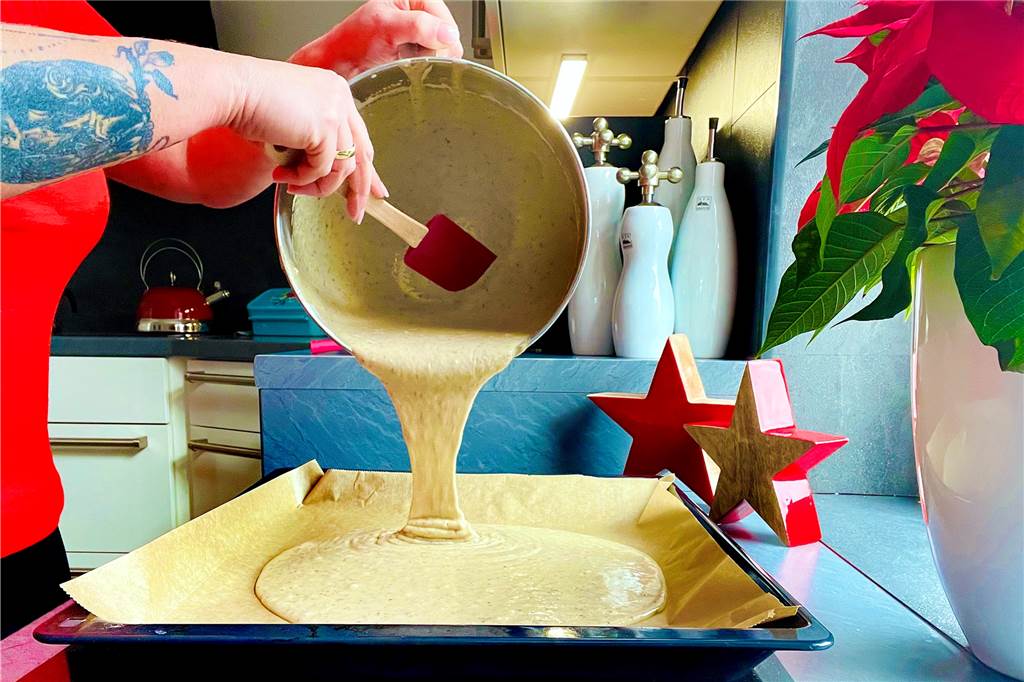 Der fertiggerührte Teig wird auf ein mit Backpapier belegtes Backblech gefüllt.