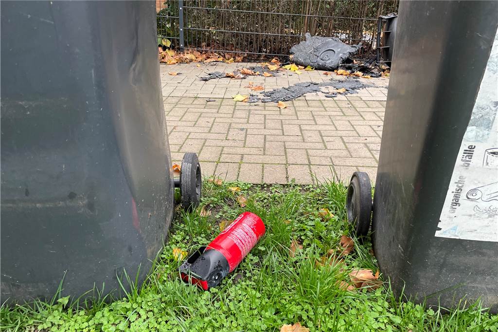 Vom Knistern der Flammen geweckt: So haben Anwohner die Mülltonnen-Brände erlebt Ein kleiner Feuerlöscher liegt zwischen zwei Mülltonnen.