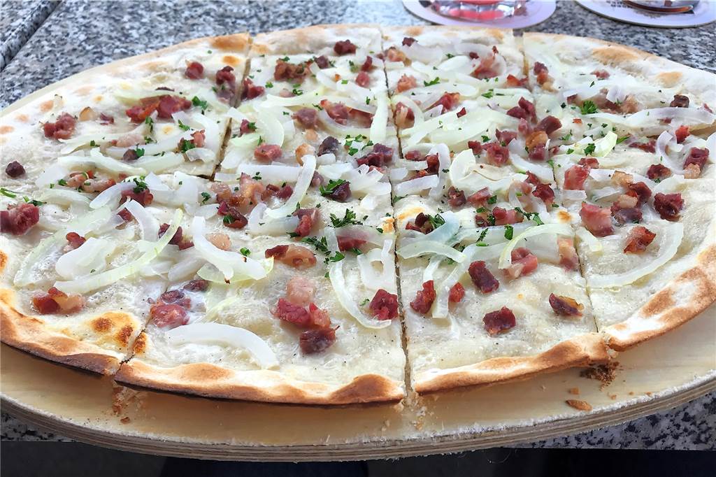 Der Flammkuchen Elsässer Art ist der Klassiker unter den Flammkuchen. Bei Schaefers wird er stilecht auf dem Holzbrett serviert.