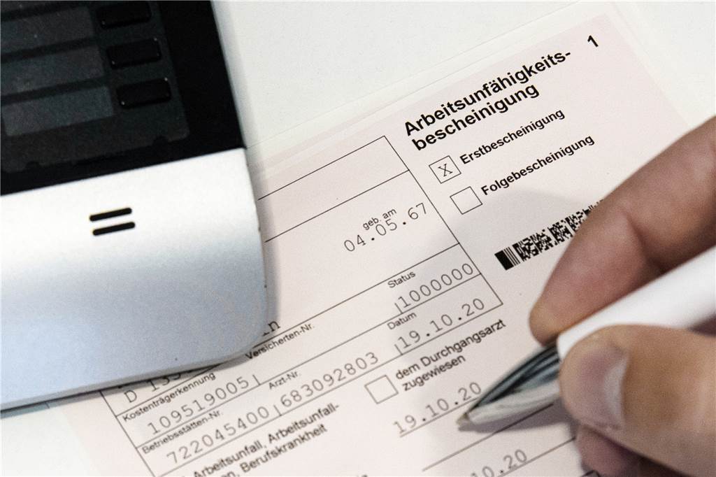 Erleichterung? Arzt sieht Problem bei digitaler Krankschreibung Ein Mensch füllt eine Arbeitsunfähigkeitsbescheinigung aus.
