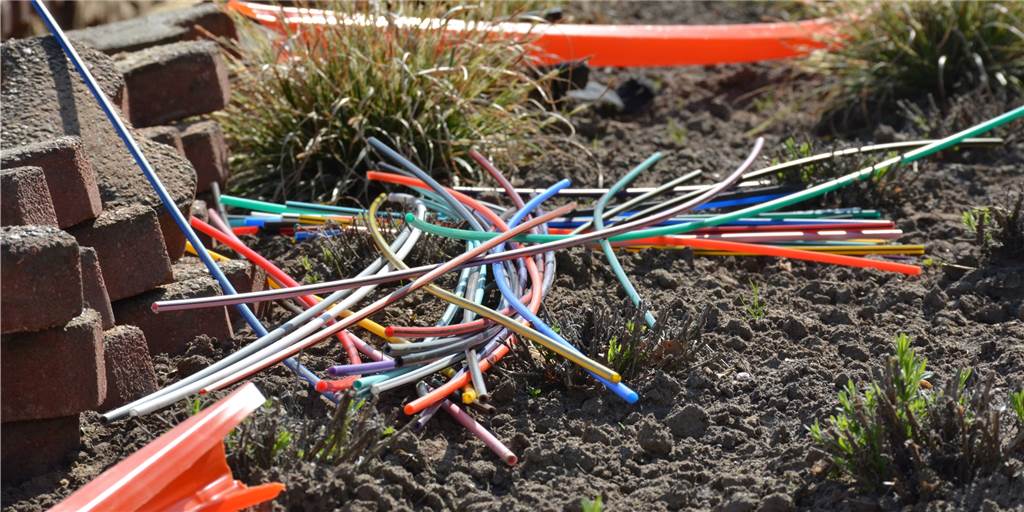 Für Castrop-Rauxel: Telekom und Westenergie müssen zusammenarbeiten Bunte Glasfaserkabel liegen auf dem Boden.