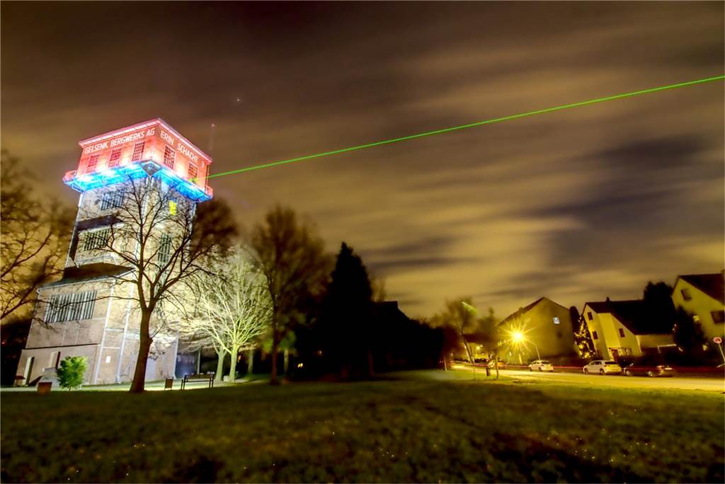 Zu sehen ist der angeleuchtete Turm der Zeche Erin, von dem ein grüner Laser abstrahlt.