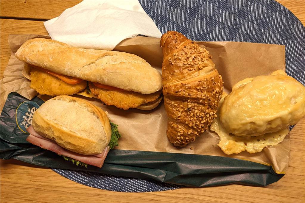 App „Too good to Go“: Mit Schnäppchen gegen Lebensmittelverschwendung Ein Schnitzelbaguette, ein Nuss-Nougat-Croissant, ein Käsebrötchen und ein mit Schinken belegtes Brötchen liegen auf einem Tisch - der Inhalt der Tüte von der Shell-Tankstelle in Hervest.