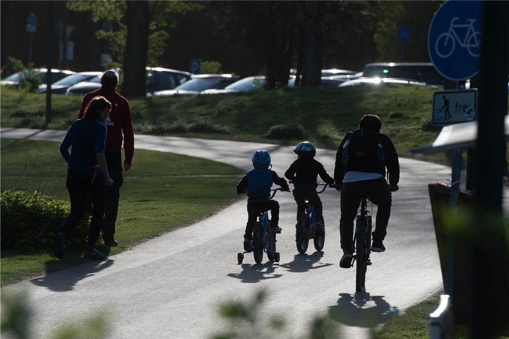 Der Wanderpfad des Kemnader Sees ist zu sehen. Konkret sieht man einen Vater mit zwei Kindern, auf Fahrrädern. Außerdem zwei Fußgänger zu rechten Seite des Bildes.