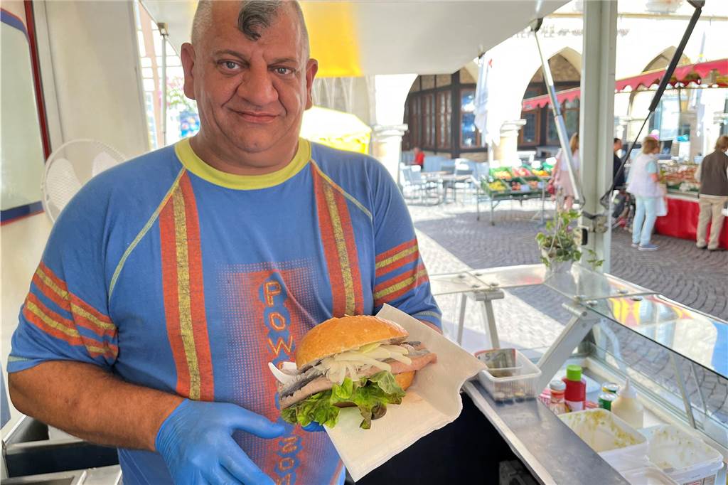 Seit 40 Jahren auf dem Wochenmarkt: Ein Fischwagen als echtes Urgestein Holger Wilk hält ein Fischbrötchen in der Hand.