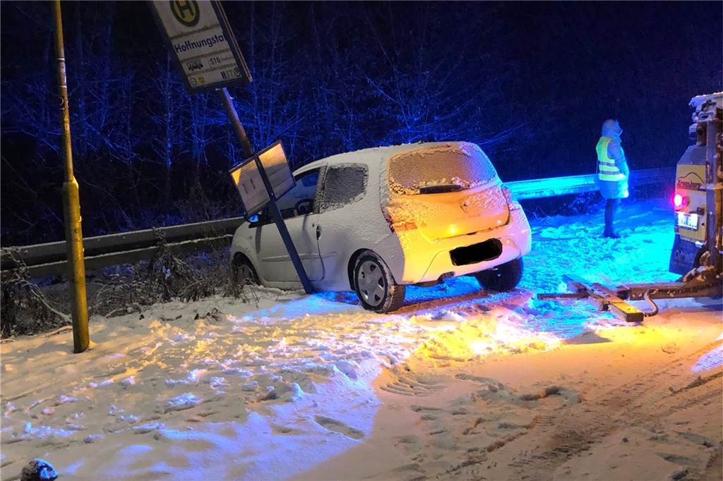 NRW: Glätte sorgt für Unfälle und Einsätze auf Straßen: Wetterdienst warnt vor Verschärfung Der weiße Kleinwagen steht im Schnee am verbogenen Haltestellenschild