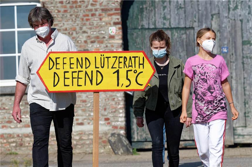 Greta Thunberg besucht Dorf in Braunkohlerevier: „Ort voller Traurigkeit“ Der letzte Bauer im Tagebaudorf Lützerath, Eckhardt Heukamp (l-r) und die Klimaaktivistinnen Luisa Neubauer und Greta Thunberg kommen mit einem Schild "Defend Lützerath Defend 1.5 Grad C" zu einem Pressetermin vor dem Hof vom Heukamp.