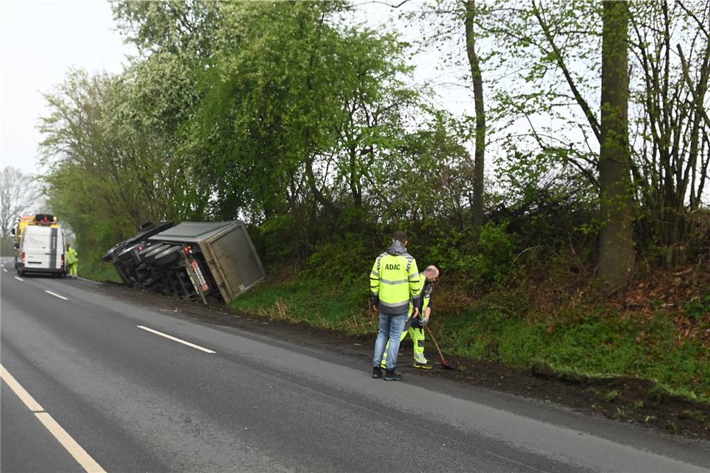 Lastwagen voller Sand kippte bei Ausweichmanöver auf die Seite Helfer eines Bergungsunternehmens an der Unfallstelle.