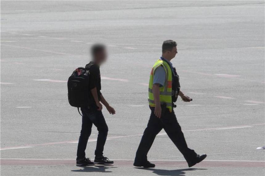Der Mann wird in Begleitung eines Bundespolizisten am Flughafen Tegel zu einem Einsatzfahrzeug geführt. Foto: Paul Zinken