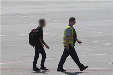 Der Mann wird in Begleitung eines Bundespolizisten am Flughafen Tegel zu einem Einsatzfahrzeug geführt. Foto: Paul Zinken