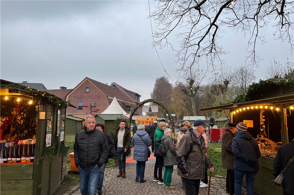 Menschen gehen durch einen weihnachtlich geschmückten Torbogen.