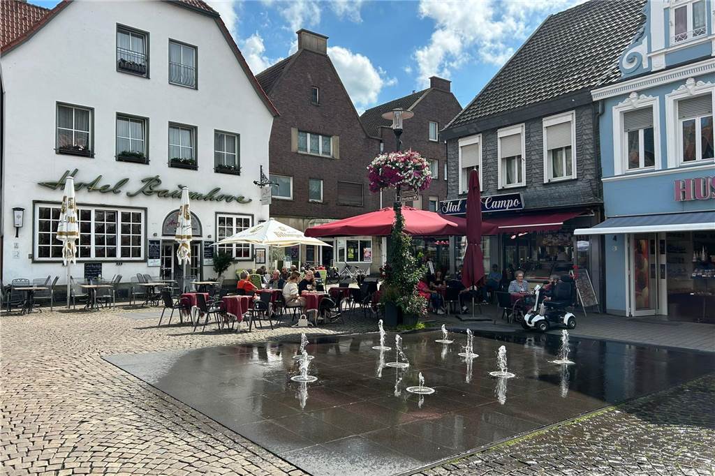 Ein Wasserspiel steht auf einem Marktplatz. 