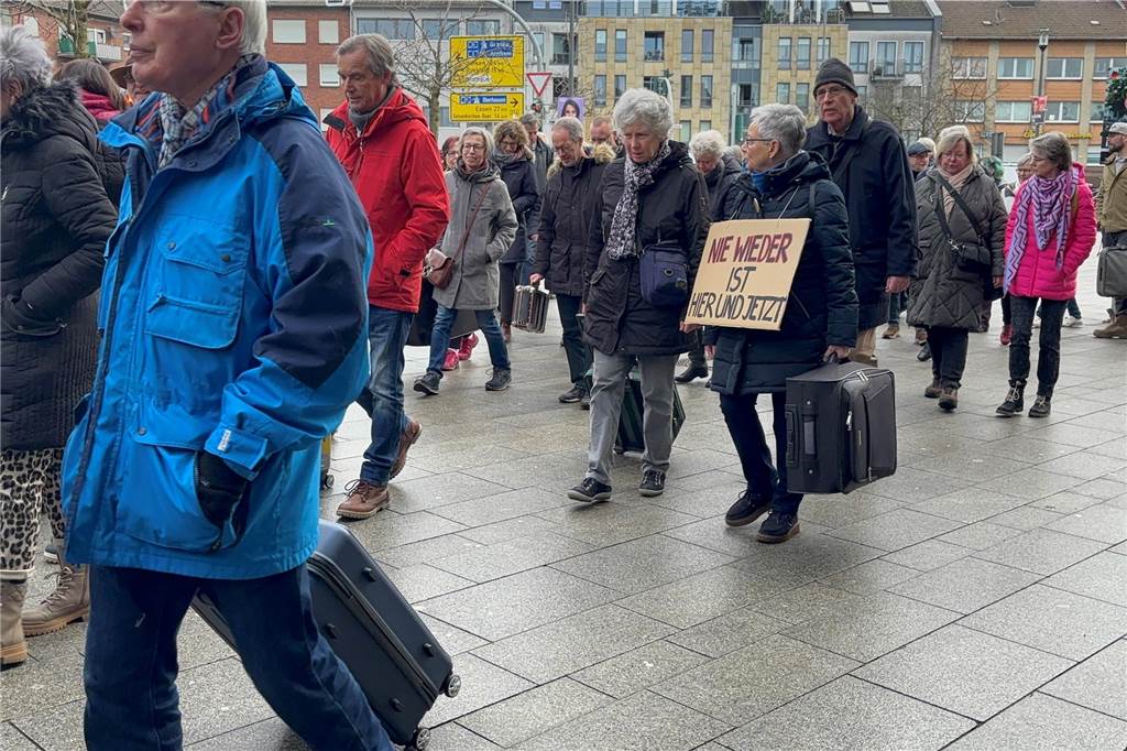 Der Beginn des Koffermarsch ist zusehen. Es werden einige Menschen, unter ihnen ein paar mit Koffern in der Hand gezeigt. 