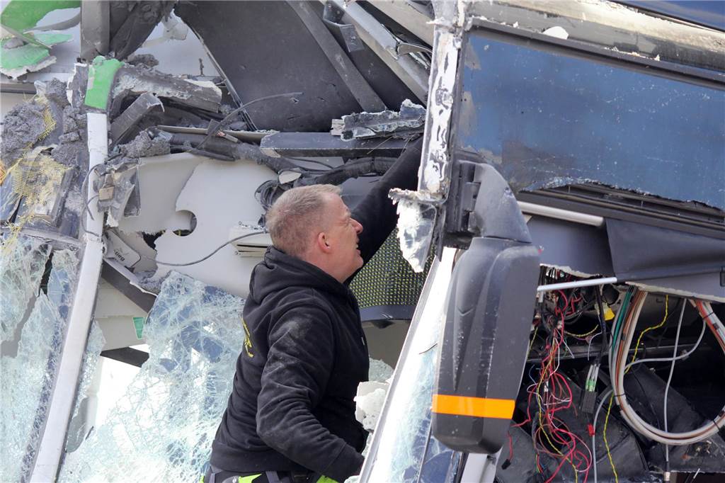 Der Mitarbeiter des Abschleppdienstes befreit lose Teile aus dem Bus-Wracke, damit sie nicht beim Schleppen auf die Straße fliegen.