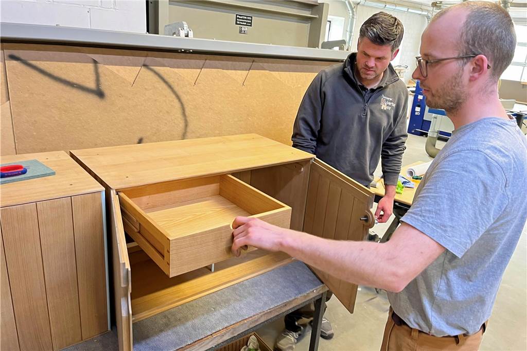 Hubertus Hols und ein Mitarbeiter werkeln an einem Schrank.
