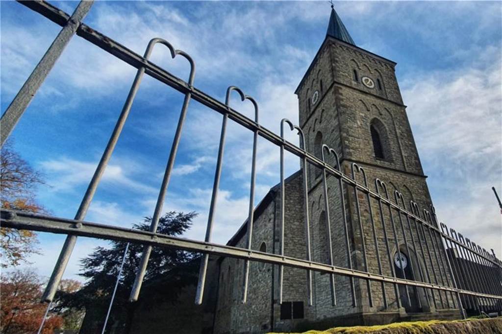 Betrügerischer Kirchenmusiker: Jagd nach Urkundenfälscher geht weiter Eine Kirche im Hintergrund - vorne ein Zaun