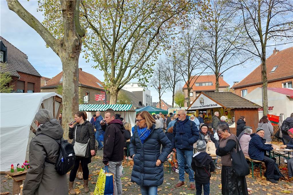 Menschen stehen unter einem Baum vor einem Stand.