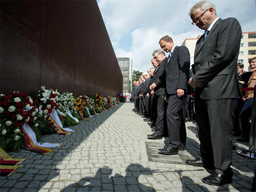 Erinnern und mahnen - Berlin gedenkt der Opfer des Mauerbaus Der Regierende Bürgermeister Müller (2.v.r.) und andere Persönlichkeiten des öffentlichen Lebens verneigen sich nach der Kranzniederlegung an der Mauergedenkstätte an der Bernauer Straße. Foto: Jörg Carstensen