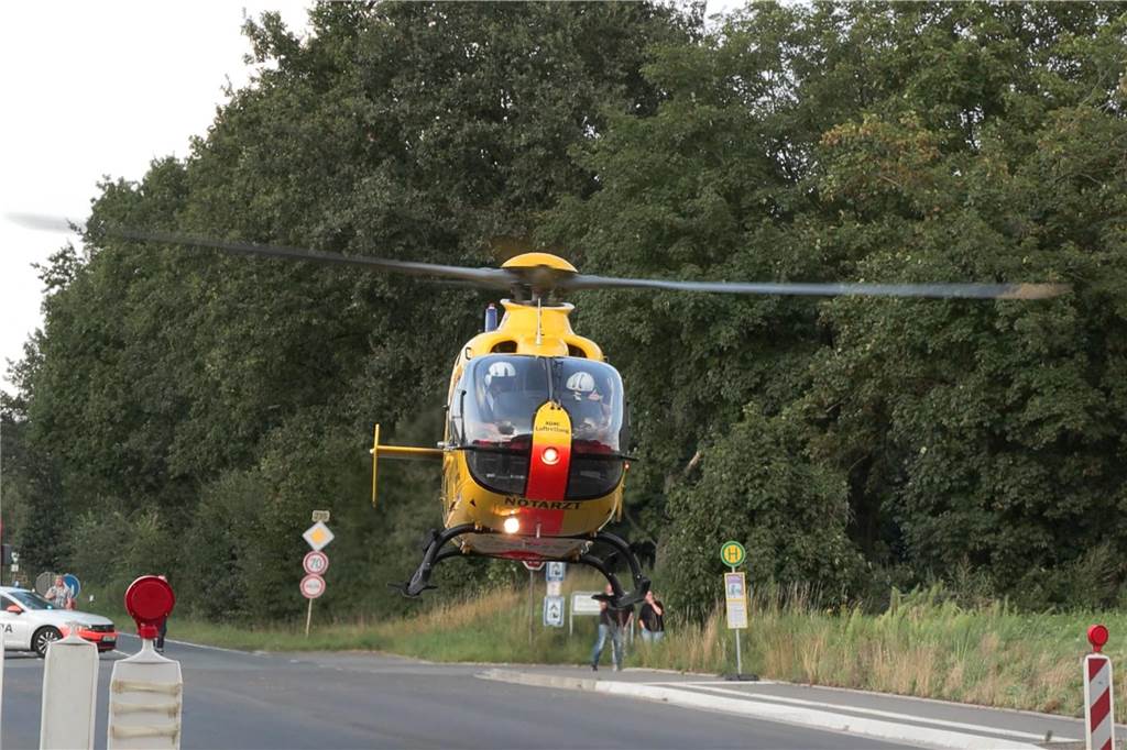 Schwerer Unfall auf Olfener Straße: Auffahrunfall zweier Motorräder - Hubschrauber landet Ein Rettungshubschrauber des ADAC hebt von einer Straße ab. Im Hintergrund stehen Menschen, die das Filmen.