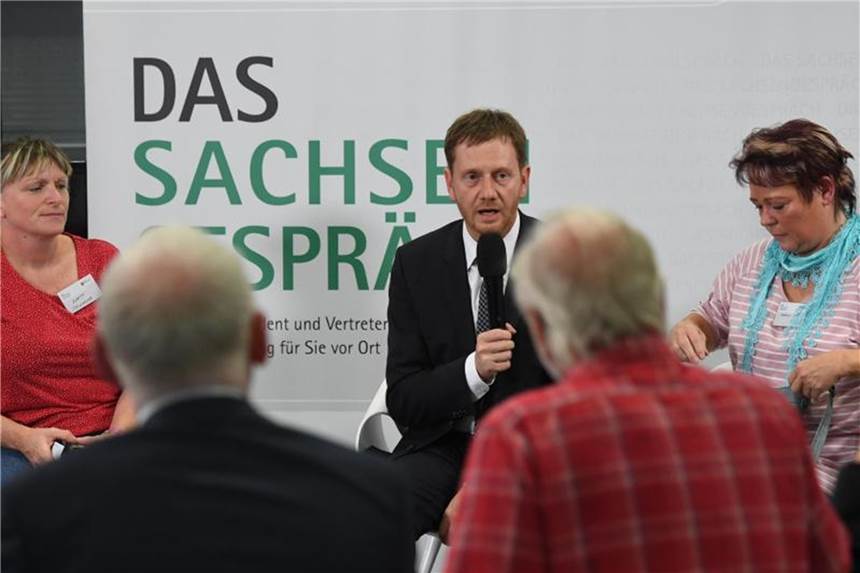 Der sächsische Ministerpräsident Michael Kretschmer (M) unterhält sich beim Sachsengespräch in Chemnitz mit Bürgern. Foto: Ralf Hirschberger