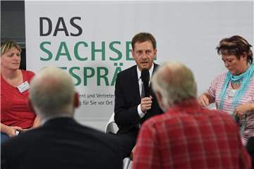 Der sächsische Ministerpräsident Michael Kretschmer (M) unterhält sich beim Sachsengespräch in Chemnitz mit Bürgern. Foto: Ralf Hirschberger