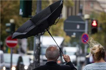 Der Schirm eines Passanten klappt in Frankfurt am Main bei Sturm und Regen um. Foto: Frank Rumpenhorst